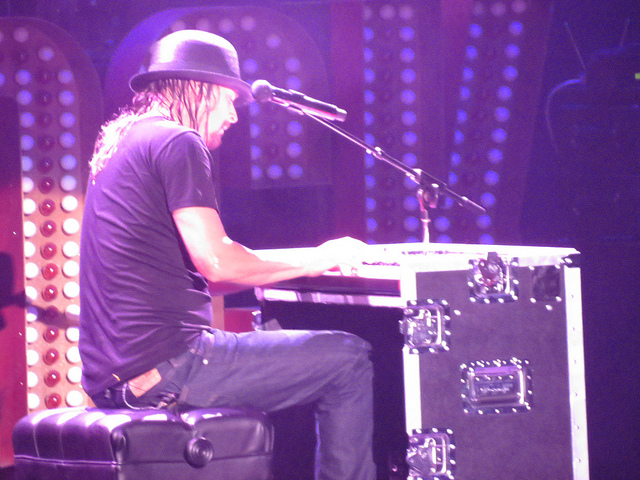 Image of musician Kid Rock play piano on a stage.